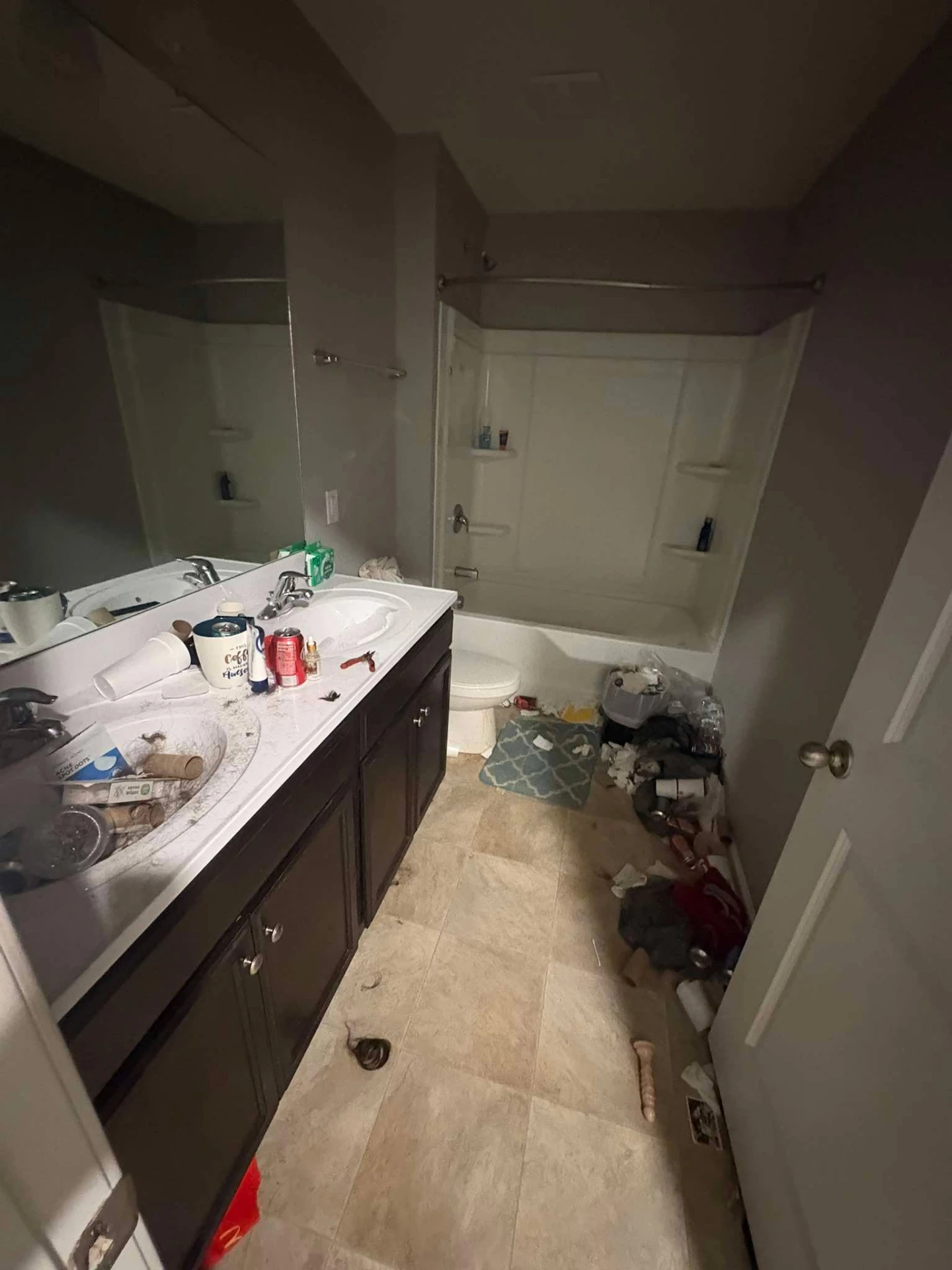 Before cleaning: guest bathroom with a cluttered vanity, debris on the floor and a dusty tub surround